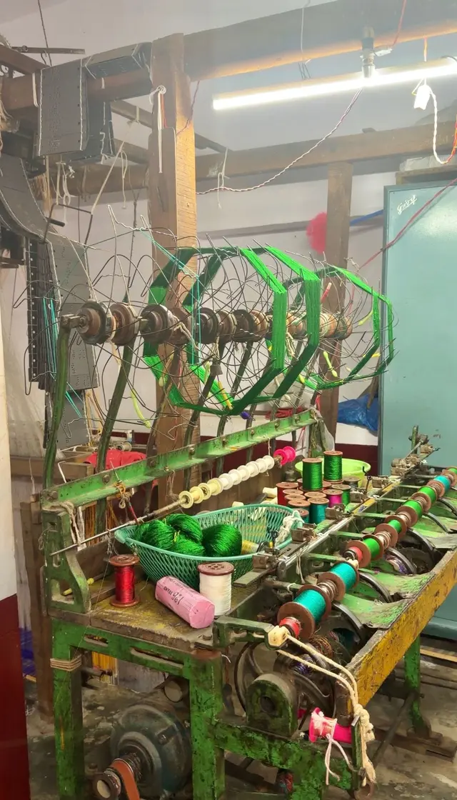 Green silk yarn winding from wire wheels onto bobbins on an old winding machine